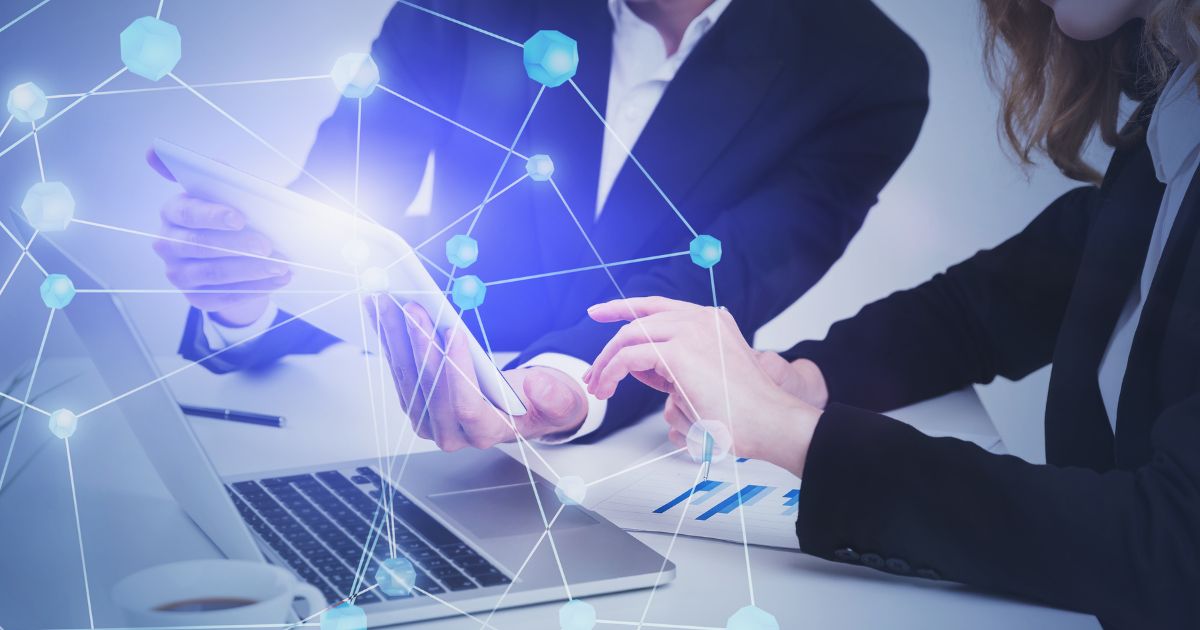 Dos profesionales analizando una tablet y una laptop con red digital superpuesta, representando el rol del partner tecnológico en proyectos de transformación digital