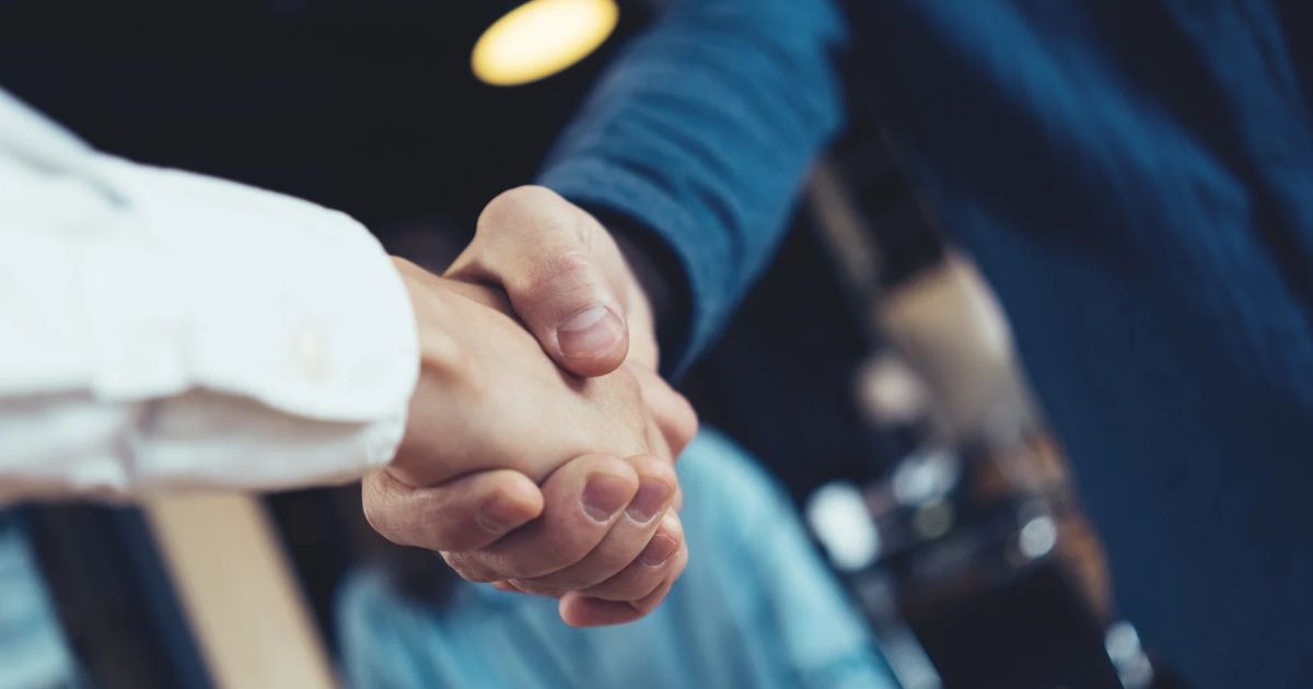 Dos manos estrechándose en representación del acuerdo de adquisición de Braze por parte de Salesforce.